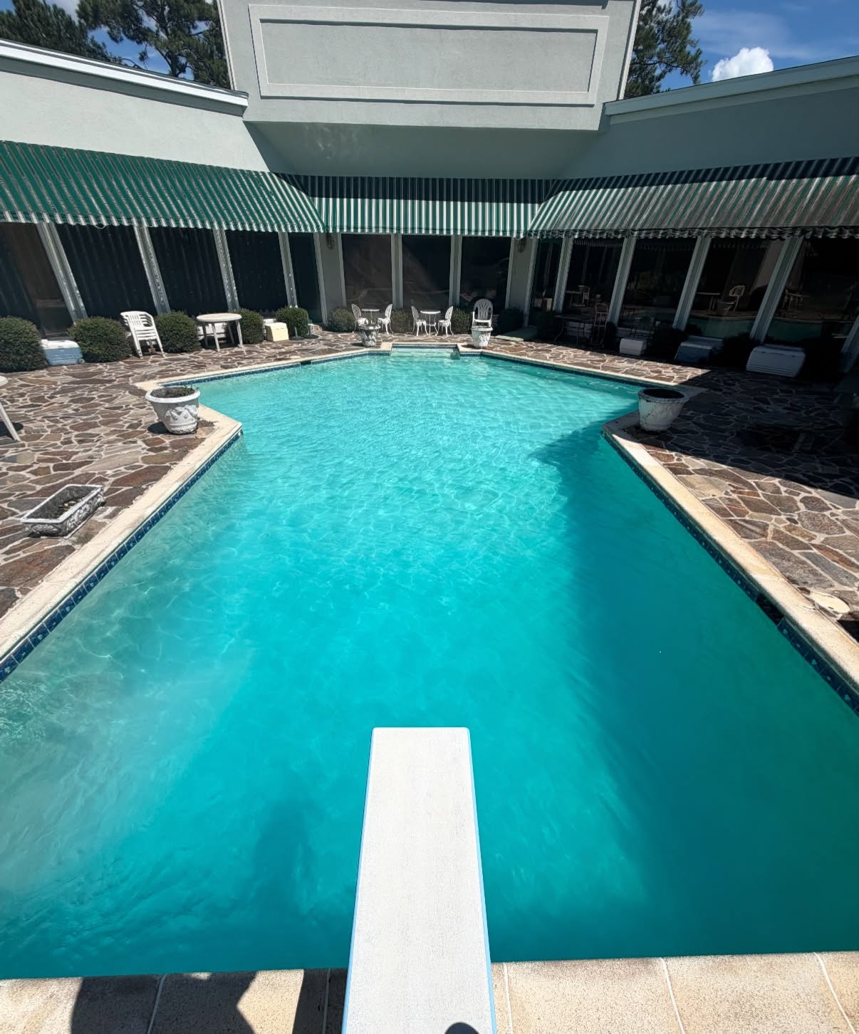 Large courtyard pool with sparkling turquoise water and diving board