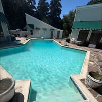 Poolside view of a clear turquoise pool alongside a stone patio